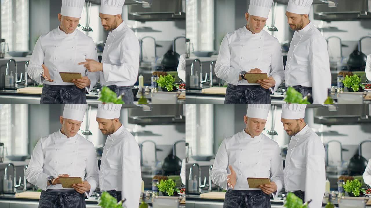 两位著名厨师就他们在平板电脑上观看的视频博客食谱交换了意见。他们在大餐馆厨房工作。