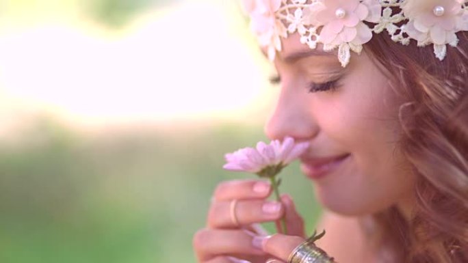 波西米亚风格的女孩在大自然中闻到一朵鲜花
