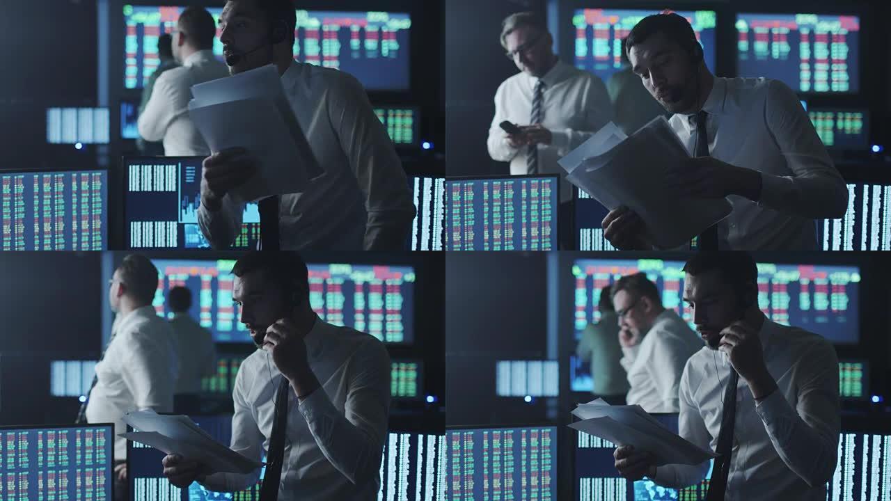 一名身穿白衬衫的股票经纪人正在一间有显示屏的黑暗监控室里打电话。