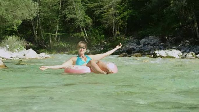 慢动作年轻女子在甜甜圈漂浮物上玩耍，在空气中泼水