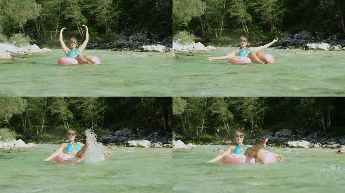 慢动作年轻女子在甜甜圈漂浮物上玩耍，在空气中泼水