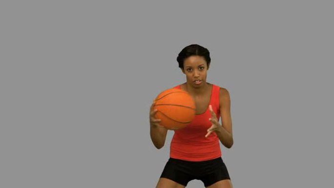 漂亮的女人在灰色屏幕上打篮球