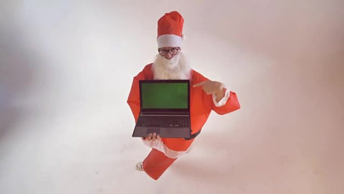 圣诞老人转过身来，显示一个全新的笔记本电脑屏幕，背景为绿色。