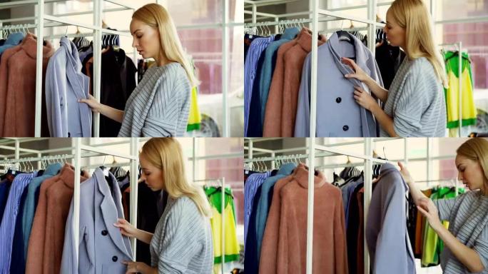 年轻女子在商店选择外套的特写镜头。首先，她正在检查织物，看纽扣，内衣和皮带，然后从衣架上脱下外套，然