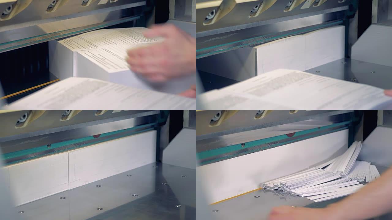 一名员工正在翻开成堆的纸，这些纸的奇怪边缘被工业切割机切断了。
