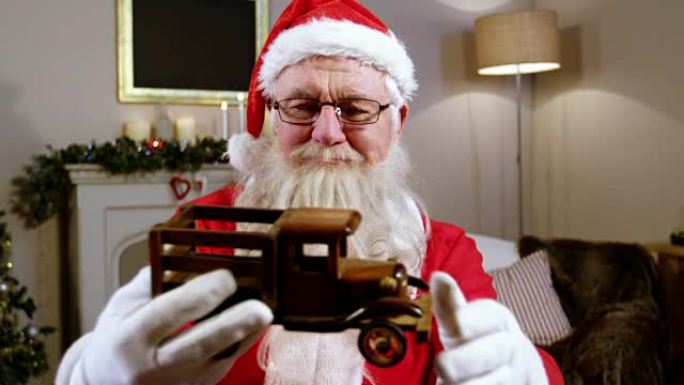 圣诞老人抱着并看着玩具车