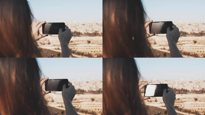 女孩拍摄以色列耶路撒冷的智能手机照片。阳光明媚的日子里，女性双手握着电话。捕捉瞬间。4K