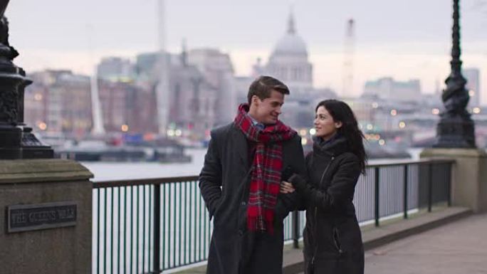 夫妇在冬季访问伦敦时沿着南岸散步