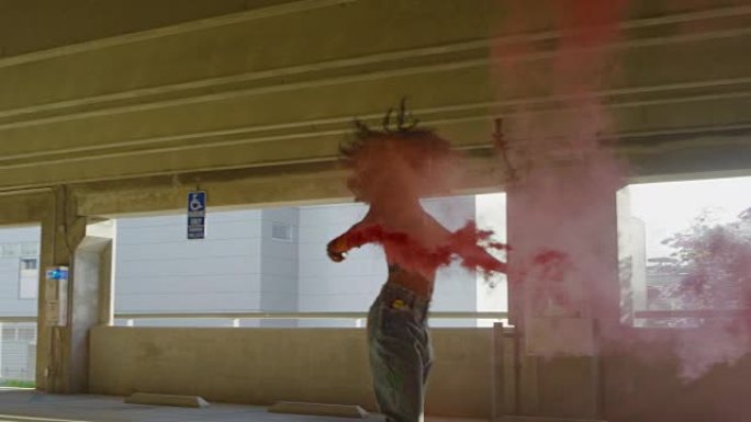 剪影年轻女子在停车场用彩色红色烟雾弹跳舞