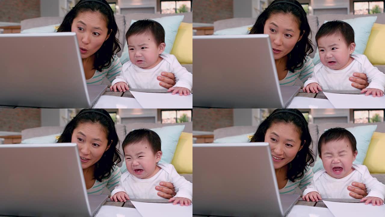 妈妈和哭闹的婴儿使用笔记本电脑