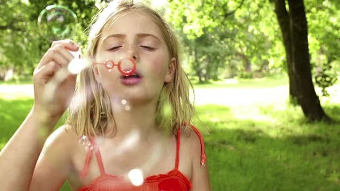 公园里的女孩用慢动作的泡泡棒吹泡泡