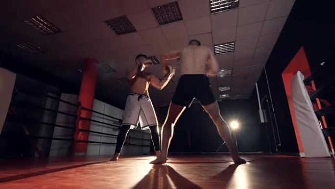 拳击手正在用胳膊和腿击中教练。MMA培训