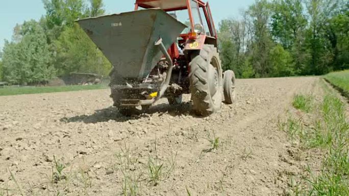 SLO MO Farmer使用拖拉机在田间撒肥
