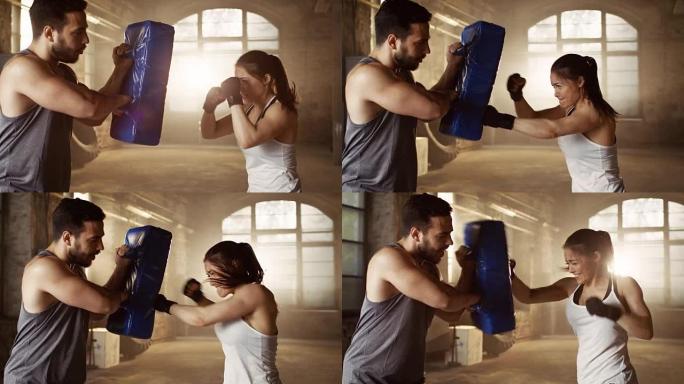 运动女子在伴侣/教练拿着的出气筒上训练拳头。她是职业拳击手，在铁杆健身房锻炼身体。