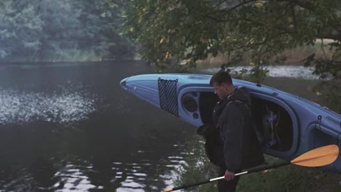 人类正把一艘蓝色皮划艇带到河边，并把它放在水上。