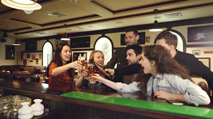 一群穿着便服的朋友在高档酒吧的柜台开会时聊天，叮当眼镜和喝酒。交流娱乐庆典概念。