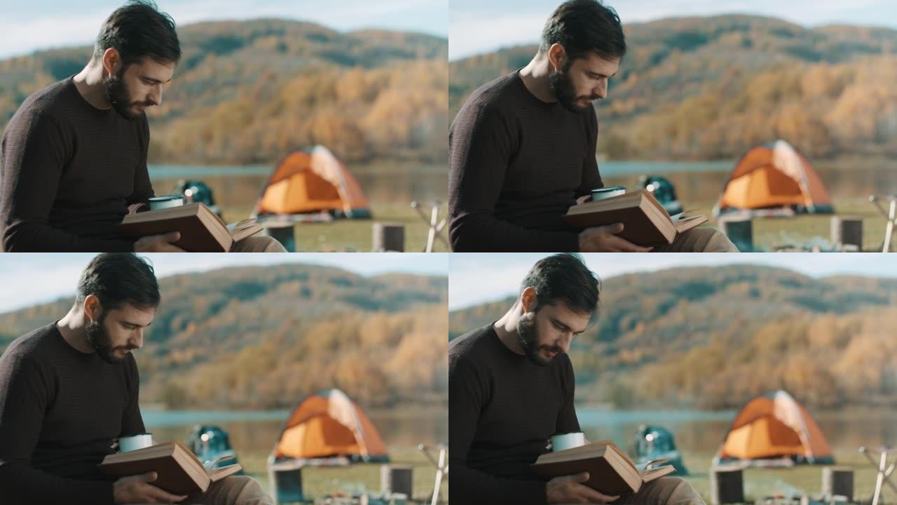 男子在露营旅行中坐着，喝咖啡和看书