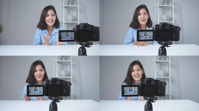 快乐微笑的亚洲女人或美容博主用刷子和相机录制视频，并在家里挥手。美女视频博客博客人物概念。多莉开枪了