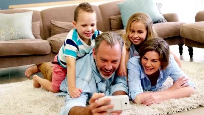 躺在地毯上并在手机上自拍的幸福家庭