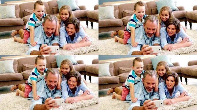 躺在地毯上并在手机上自拍的幸福家庭
