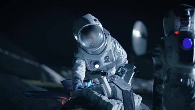 两名宇航员穿着宇航服在外星为火星表面探索探险准备太空车。太空旅行和太阳系殖民概念。