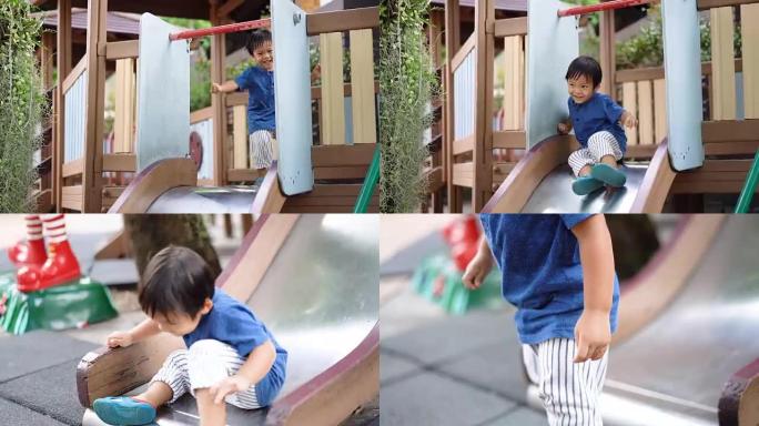 快乐的亚洲小男孩从儿童滑梯上往下走。
