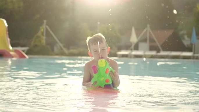 慢动作: 快乐的孩子在有趣的水上公园美丽的金色夏日日落时，用水枪将水滴直接喷入相机