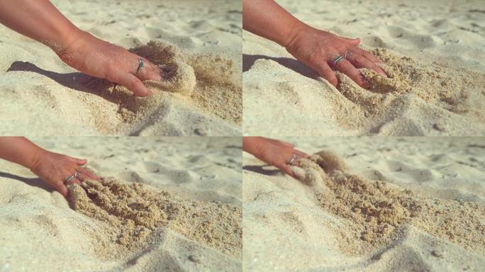 慢动作: 顽皮的年轻女子用手指在沙滩上画画。
