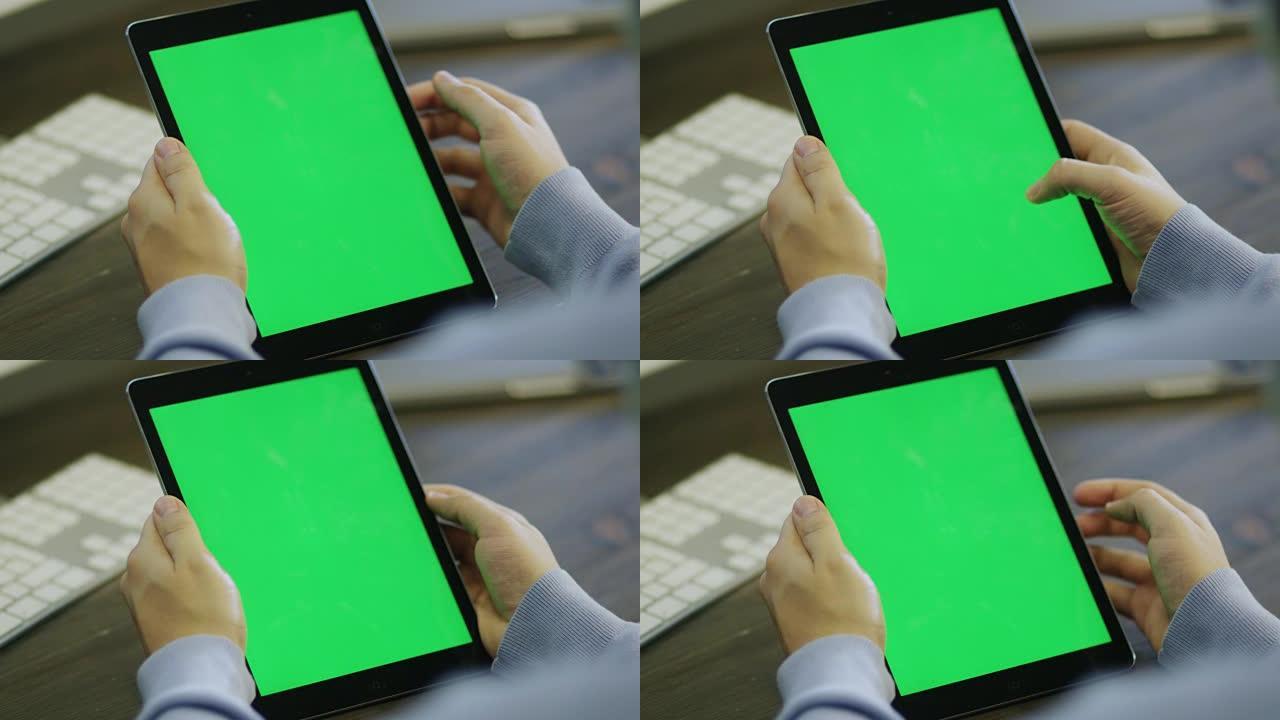 设计师在工作中使用带有绿色屏幕的数字平板电脑。
