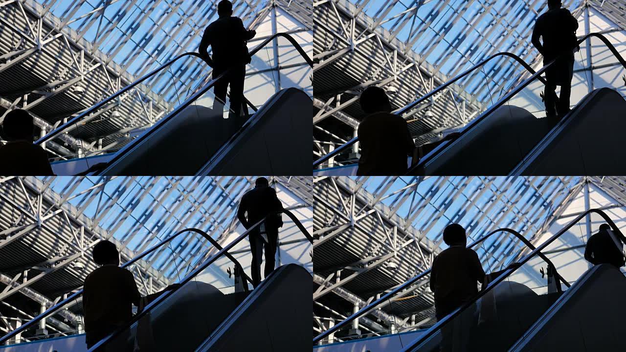 现代玻璃建筑和自动扶梯上商人的移动剪影