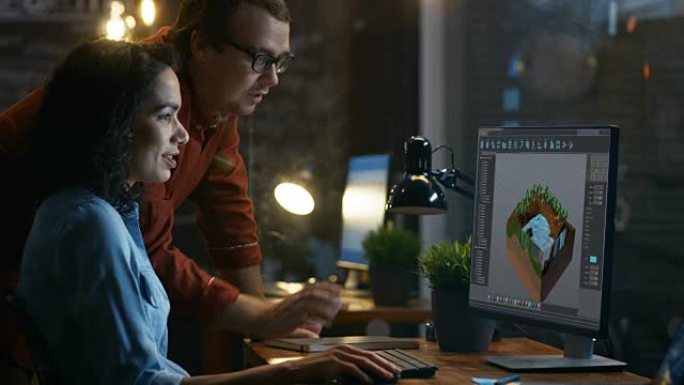 女性3D视频游戏开发人员在她的计算机上进行关卡设计，并与项目经理进行交谈。他们在创意办公室工作。