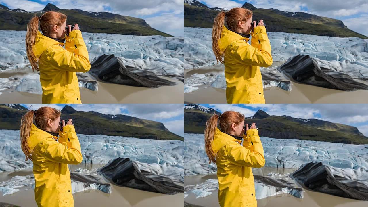 穿着黄色雨衣的女人用相机拍摄冰川