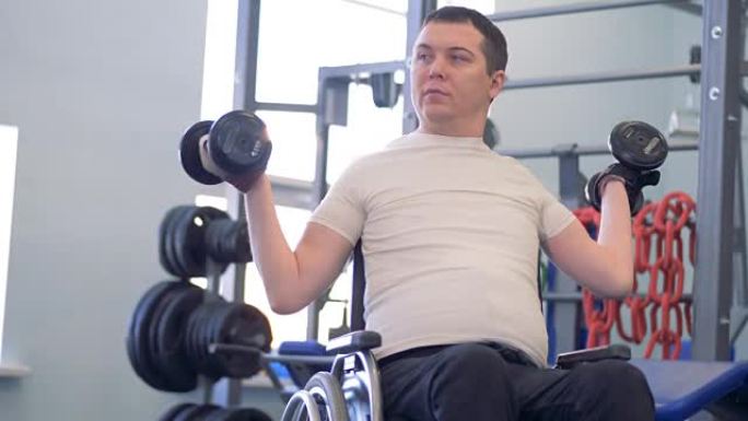 在健身房里训练一个有两个哑铃的残疾人