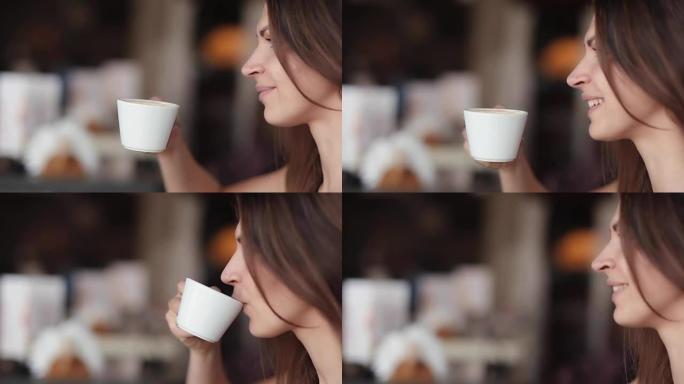 漂亮女人喜欢喝杯咖啡。一个漂亮女孩的侧景，有一杯美味的卡布奇诺或拿铁，侧景