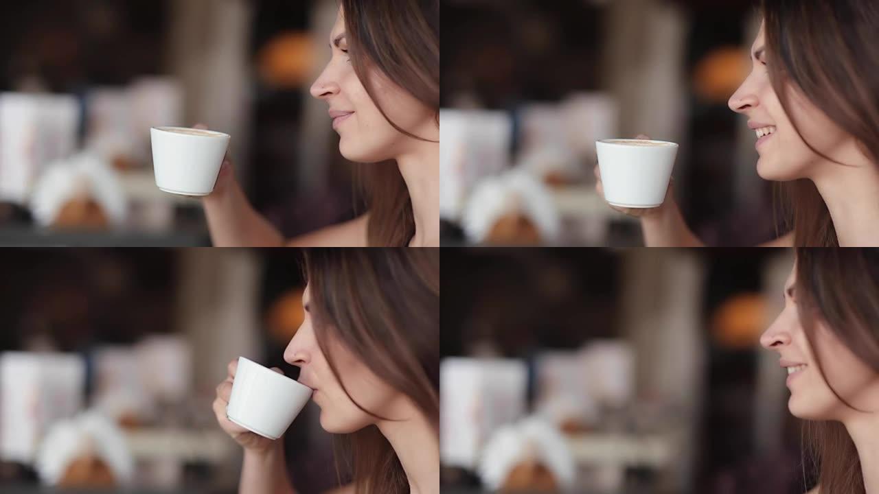漂亮女人喜欢喝杯咖啡。一个漂亮女孩的侧景，有一杯美味的卡布奇诺或拿铁，侧景