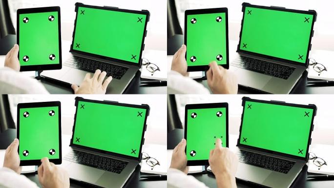 亚洲男子使用平板电脑和带有空白绿屏的现代笔记本电脑