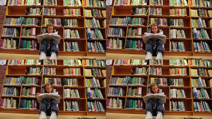 漂亮的学生坐在图书馆的地板上看书