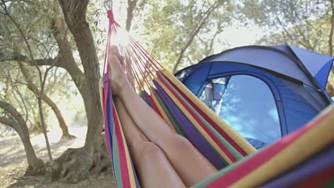 女人在阳光明媚的夏季露营地的吊床上放松