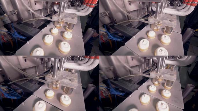 工业冰淇淋机正在用一排威化饼杯朝相反的方向移动并填充它们
