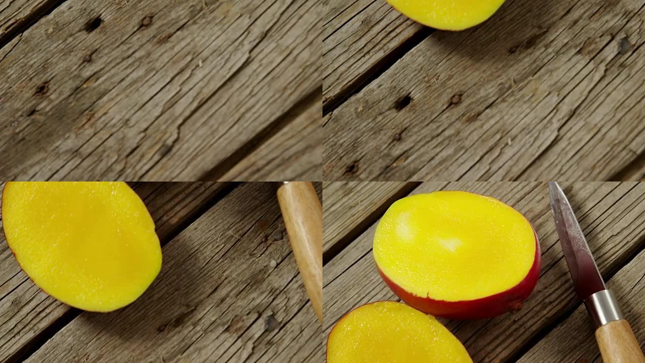 木桌上的芒果和刀减半