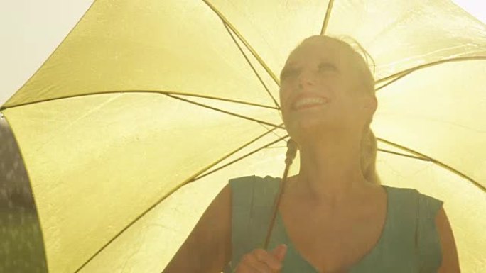慢动作快乐的女人用雨伞旋转，用手感受雨水