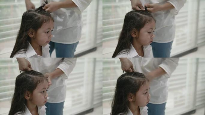 莫特正在为她的女儿做头发，