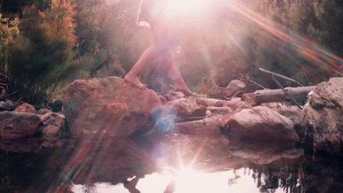 穿着波西米亚花裙的女孩在湖边踩着石头