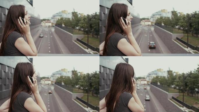 性感的女商人使用智能手机站在俯瞰道路的桥上，steadicam拍摄。慢mo