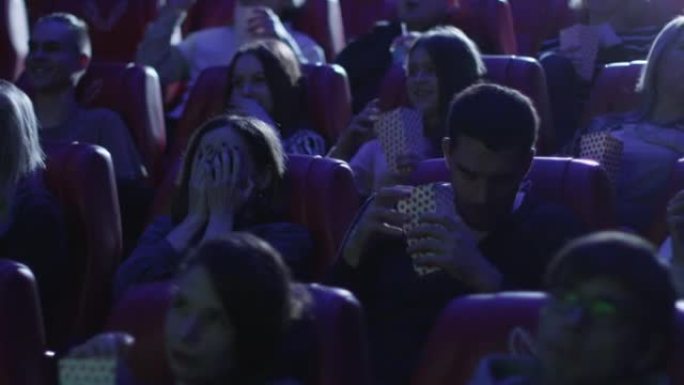 一群人在电影院看恐怖片放映时感到害怕。