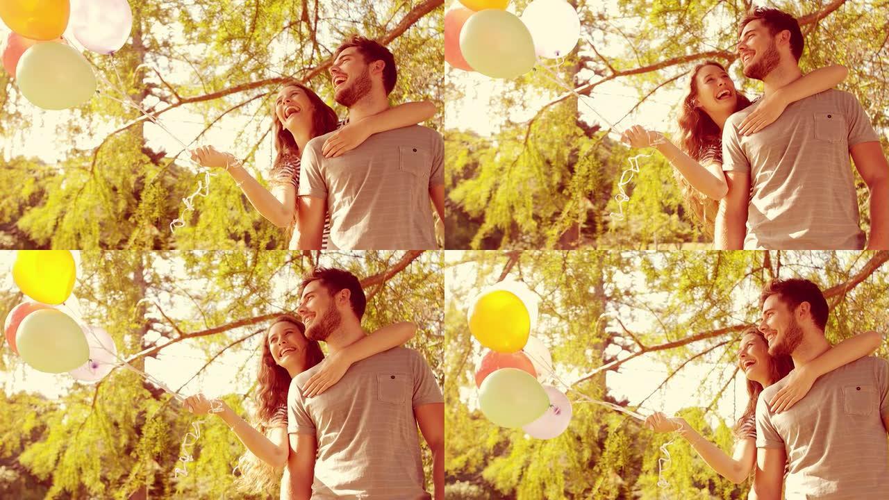 幸福的夫妻在公园里拥抱并拿着气球