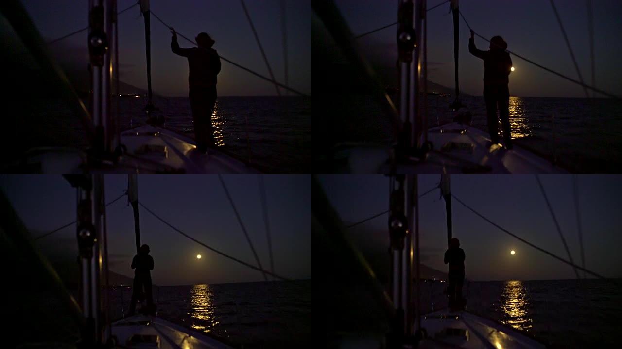 4k剪影女人走在宁静的夜晚海洋的帆船甲板上，月圆，实时