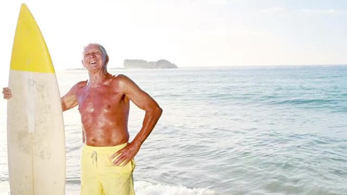 退休老人在海边拿着冲浪板