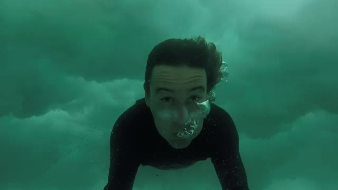 慢动作特写: 快乐的年轻冲浪者做鸭子潜水