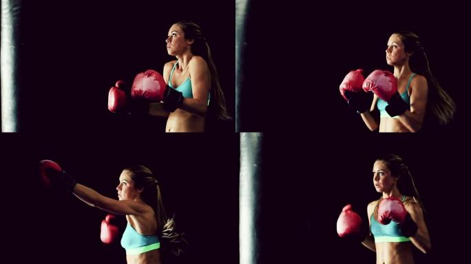 美丽的年轻女运动员锻炼自我防卫与拳击手套和身体袋。